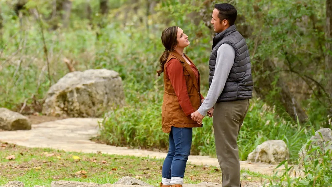 Couple standing and holding hands on a path in the forest.