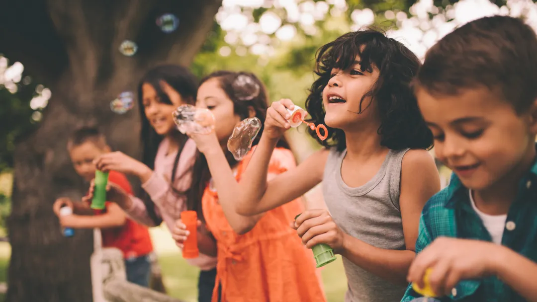 A group happy children blowing bubbles during the summer.