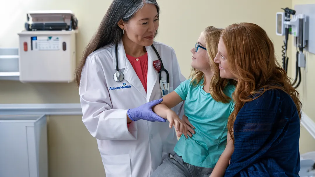 A Centra Care Physician Checks a Little Girl's Arm With Her Mom Watching