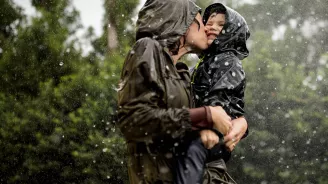 Mom and little boy playing in the rain.