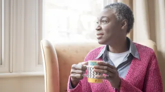 Enjoying her morning coffee, a mature woman reflects on life.