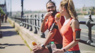 Two runners eat a healthy snack.