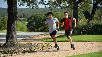 Two young men running outside on a path.