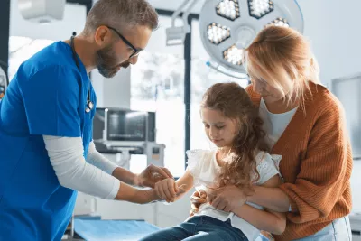 Doctor evaluating at a young girl's arm.
