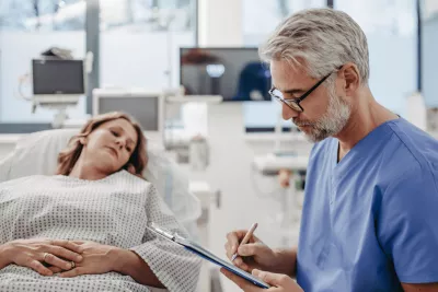 Woman in ER while doctor writes notes.