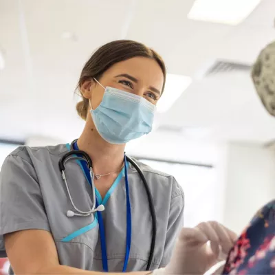 A Nurse Smiles as She Prepares a Patient for an Injection.