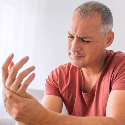 A Man Looks at the Palm of His Hand in Pain