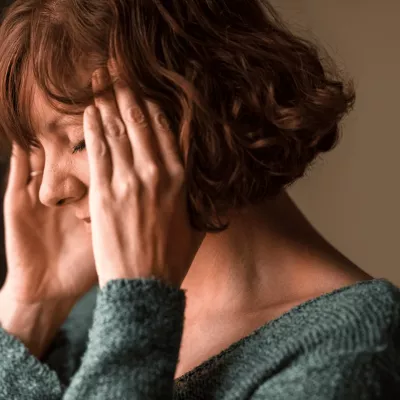 Woman with a migraine holding her head.