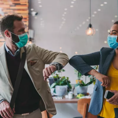 Masked coworkers elbow bump