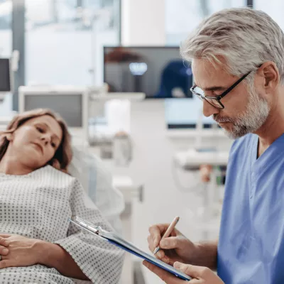 Woman in ER while doctor writes notes.