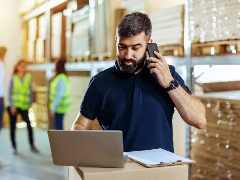 Man on cellphone looking at laptop.