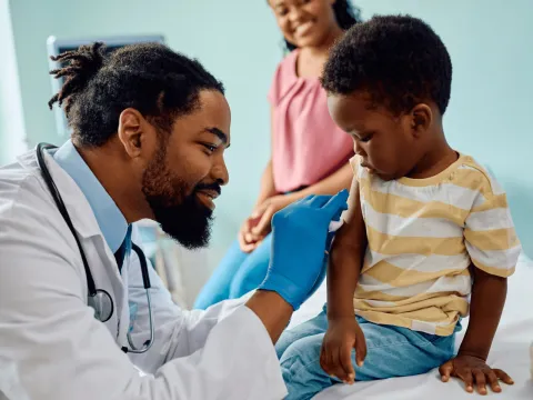 A Physician Prepares to Give a Young Patient a Vaccine
