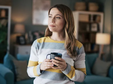 Woman holding a cup of coffee in her living room
