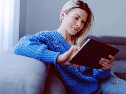 A woman on her couch and using her tablet