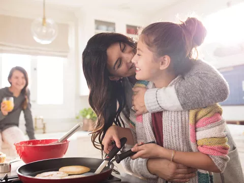 A mother and her teenage daughter enjoying their time cooking breakfast