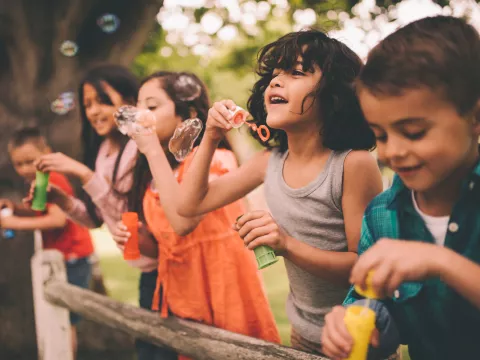 A group happy children blowing bubbles during the summer.