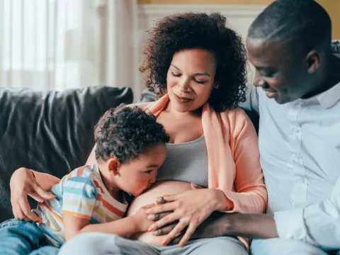 A pregnant woman with her husband and son.