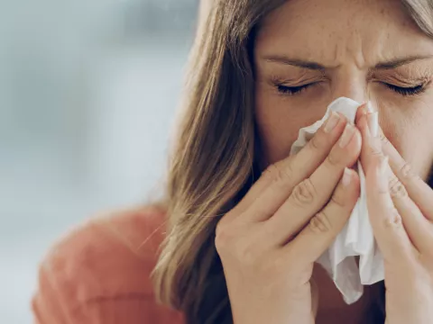 A woman sneezing into a tissue.