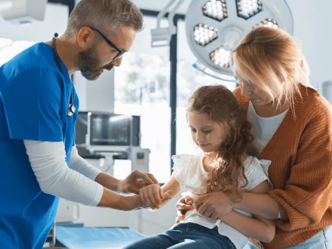 Doctor evaluating at a young girl's arm.