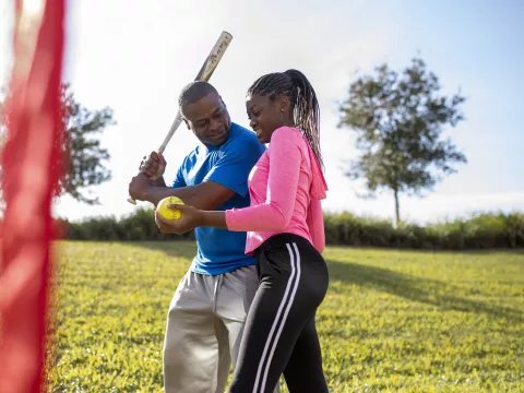 A father and daughter playing softball outdoors