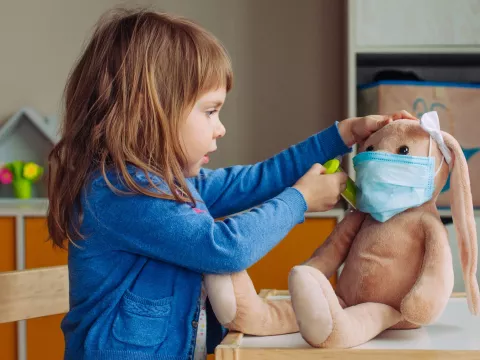 A child playing doctor with a stuffed animal.