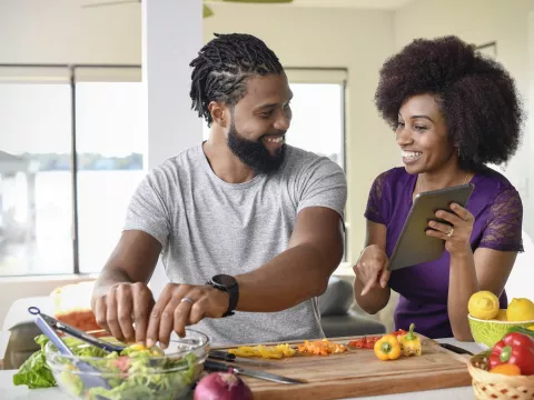 A couple making a salad from a recipe.