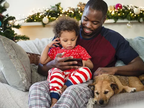 A father an son sit together on the couch during the holiday season. 