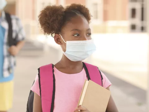 A girl attending school and wearing a mask. 