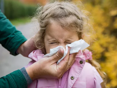 With the help of her mom, a little girl blows her nose