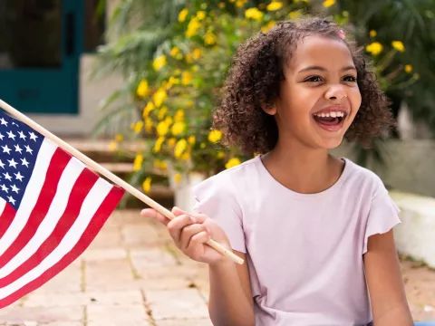 A young girl waves an American flag.