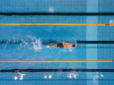 An olympic swimmer paddles freestyle through the water