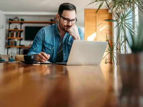 A gentleman indoors and focused on a task on his laptop