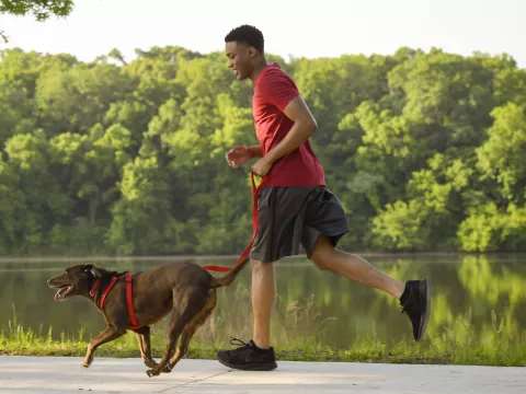 A man running outside with his dog.