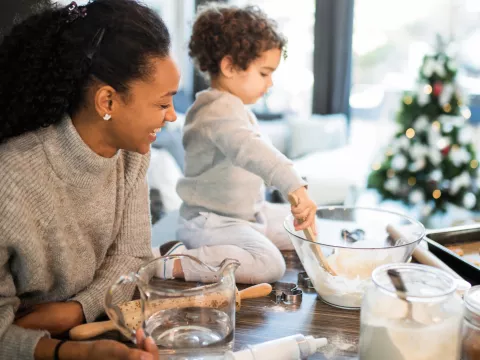 A mom and her toddler bake Christmas cookies together.