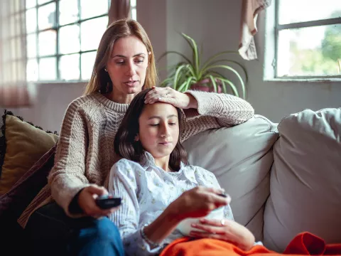 Hero Mom Comforts Her Sick Teenage Daughter on the Couch at Home.