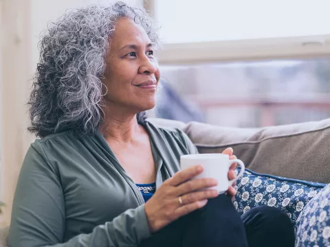 A woman sits by the window drinking tea.