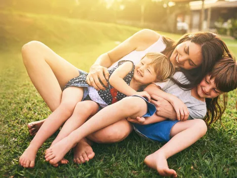 Mother playing with her children on the lawn.