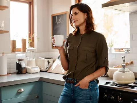 A woman drinking tea in her kitchen.