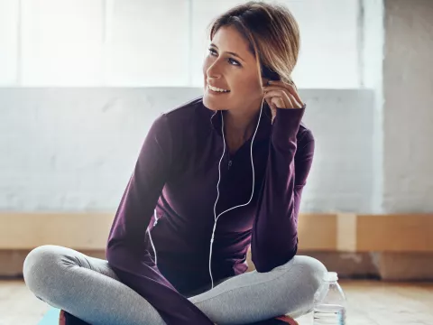 A woman wearing headphones and exercise clothes.