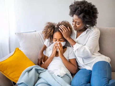 A mother tending to her sick daughter on their couch