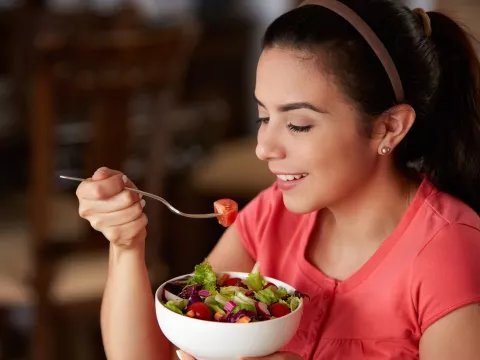 A woman eating a bowl of health food.