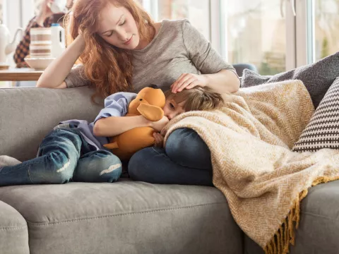 Sick child with mom on couch.