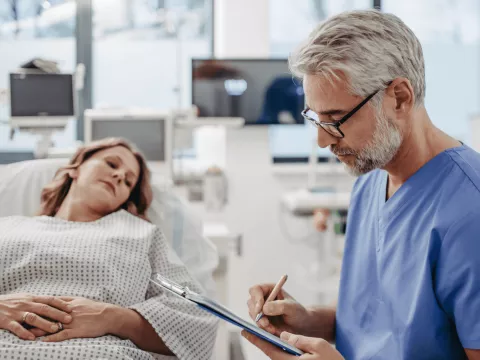 Woman in ER while doctor writes notes.