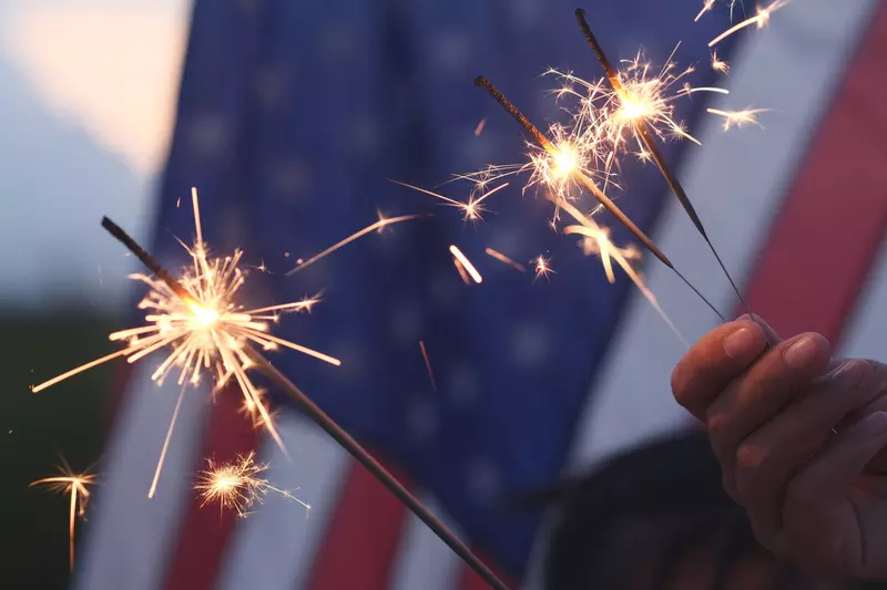 3 Sparklers Burn in Front of The American Flag