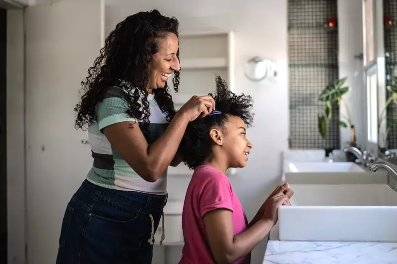 A Mother Helps Her Daughter with Her Hair in The Bathroom.