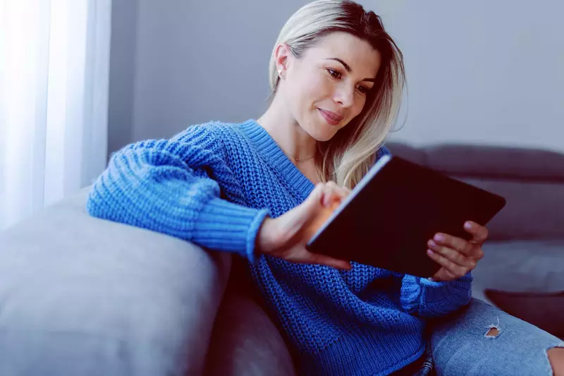 A woman on her couch and using her tablet