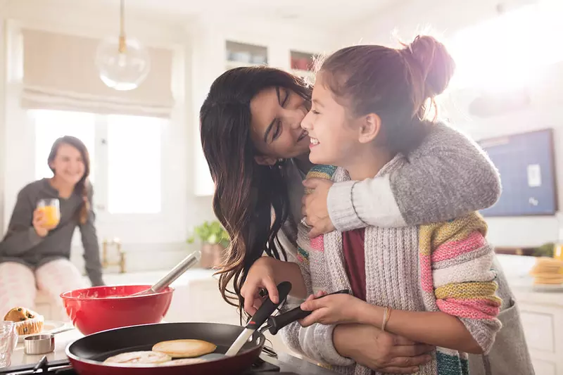 A mother and her teenage daughter enjoying their time cooking breakfast