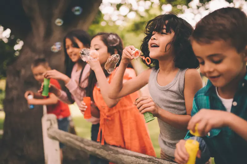 A group happy children blowing bubbles during the summer.