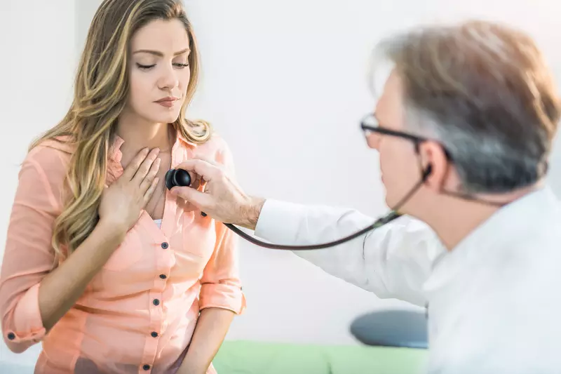 A doctor checking a woman's heart beat
