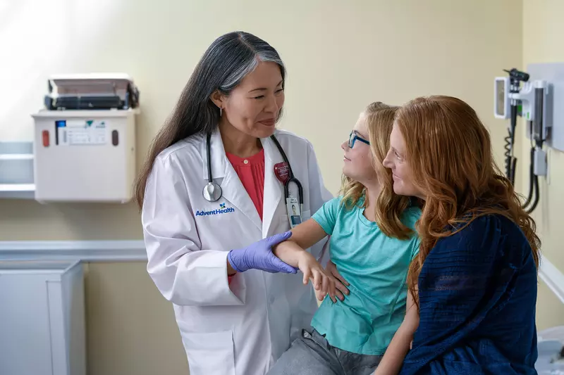A Centra Care Physician Checks a Little Girl's Arm With Her Mom Watching